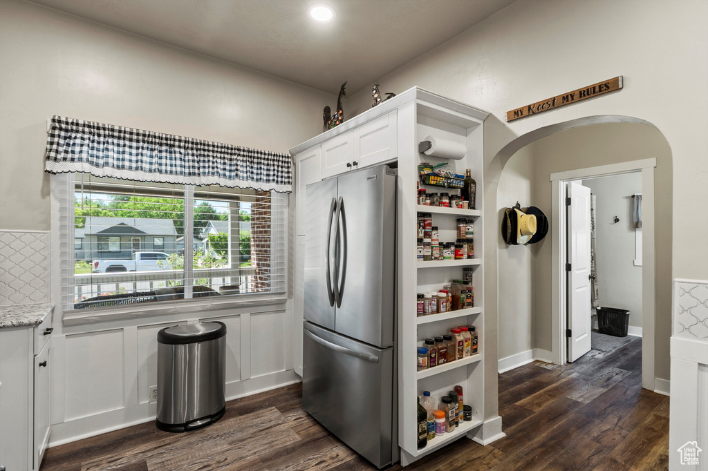 Kitchen featuring freestanding refrigerator, white cabinetry, dark wood-type flooring, and light stone countertops