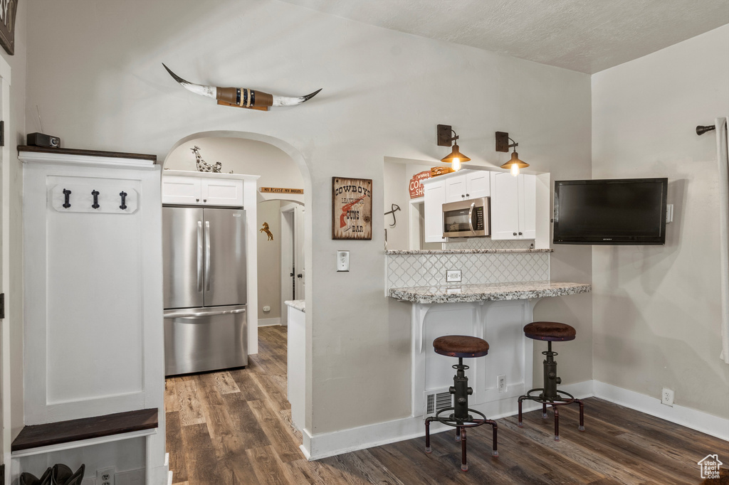 Kitchen featuring stainless steel appliances, white cabinetry, and dark wood-style floors