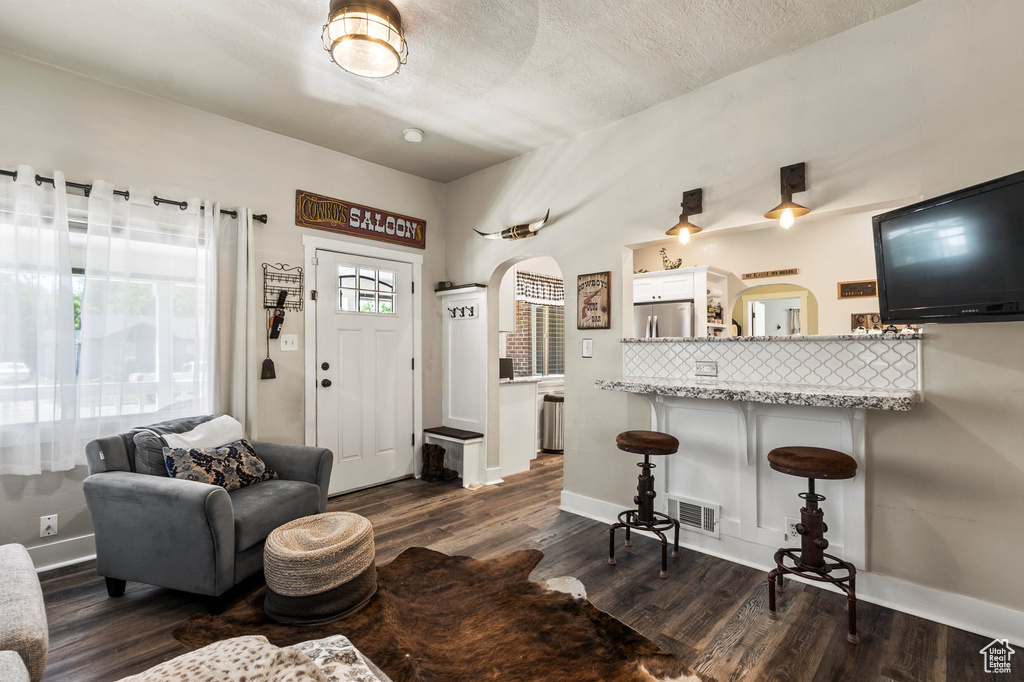 Living area with arched walkways and dark wood-type flooring