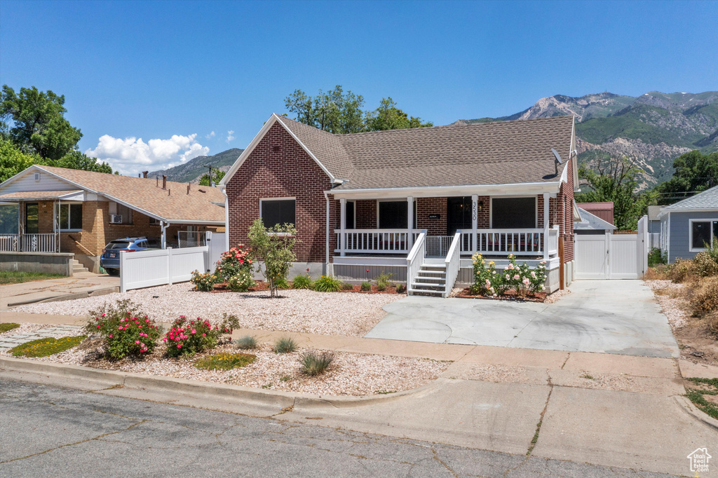 View of front of home featuring a gate, brick siding, a porch, and a mountain view
