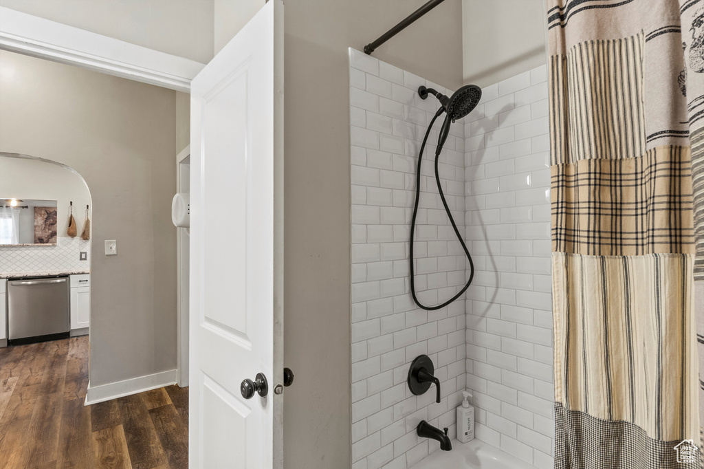 Bathroom with shower / tub combo with curtain, wood finished floors, and tasteful backsplash