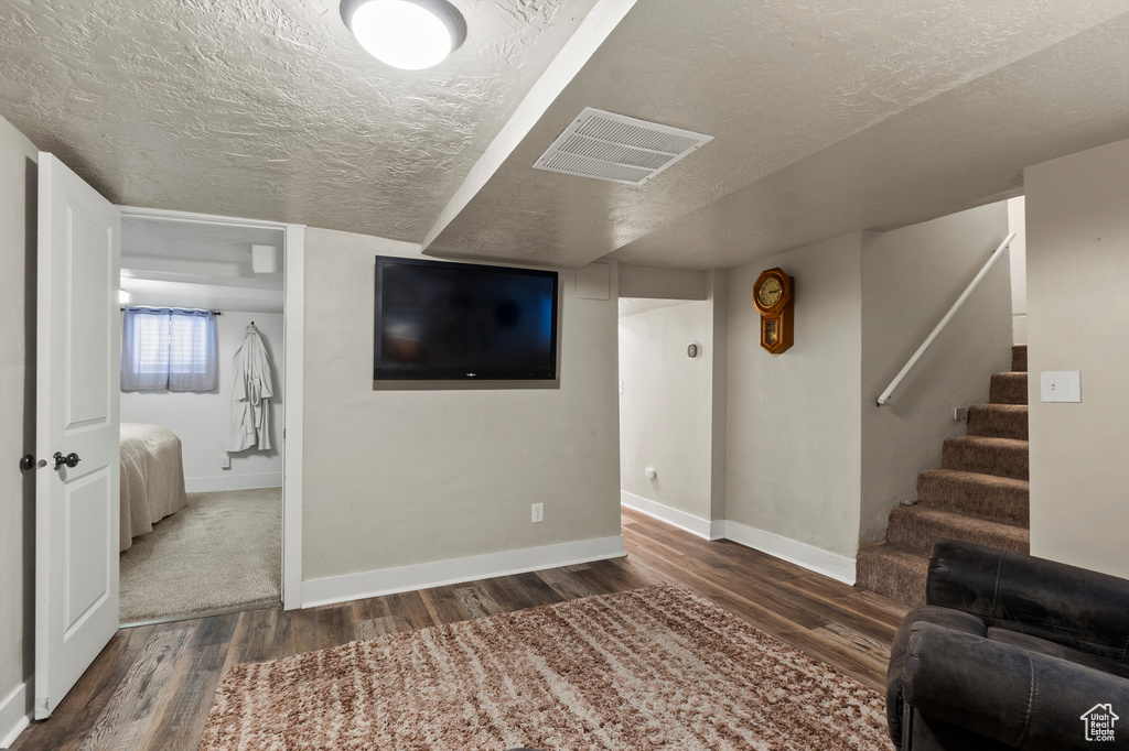 Living area featuring wood finished floors, a textured ceiling, and stairs