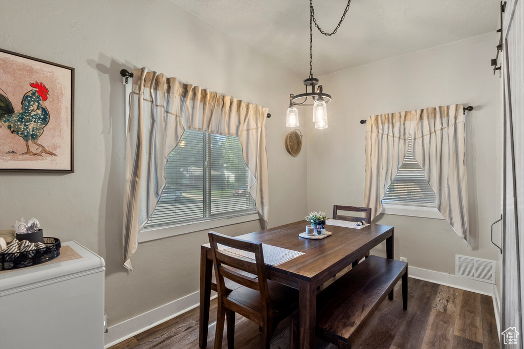 Dining space with dark wood-type flooring and a chandelier