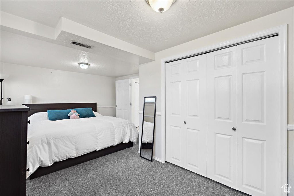 Bedroom with a textured ceiling, carpet, and a closet