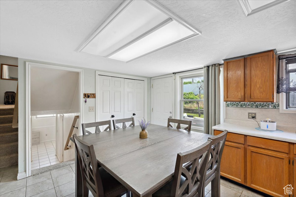 Dining area with light tile patterned flooring, stairs, and a textured ceiling