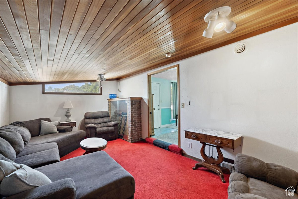 Living room featuring carpet floors, wooden ceiling, and a brick fireplace