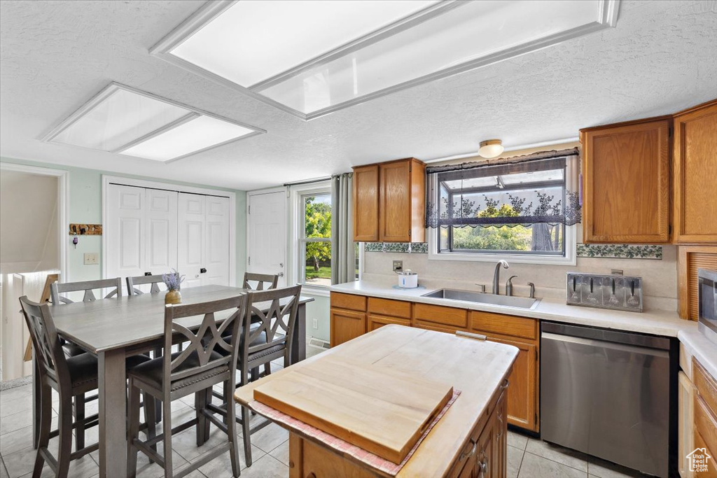 Kitchen featuring appliances with stainless steel finishes, brown cabinetry, light tile patterned floors, tasteful backsplash, and a textured ceiling