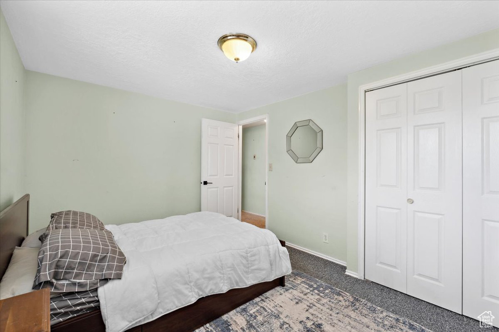 Carpeted bedroom featuring a closet and a textured ceiling