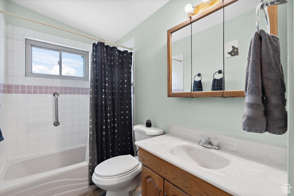 Full bathroom featuring vanity, vaulted ceiling, and shower / tub combo