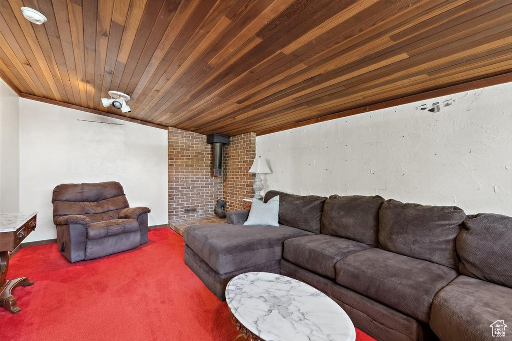 Carpeted living room with a wood stove and wooden ceiling
