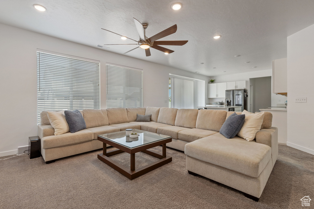 Living area with ceiling fan, light carpet, baseboards, and recessed lighting