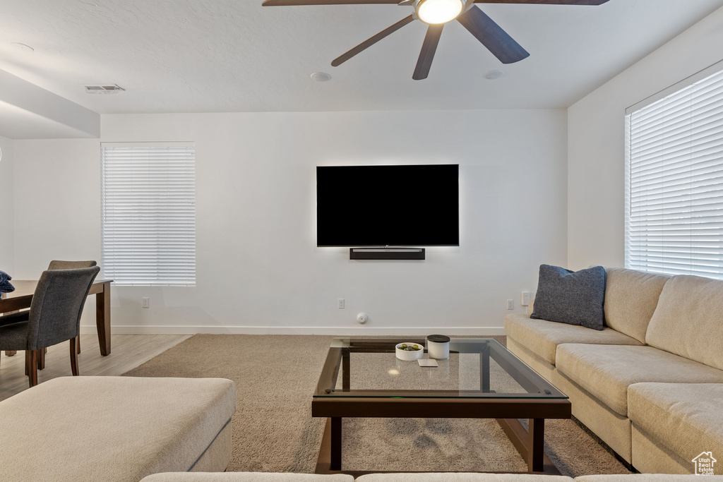 Living room with ceiling fan, baseboards, and light carpet