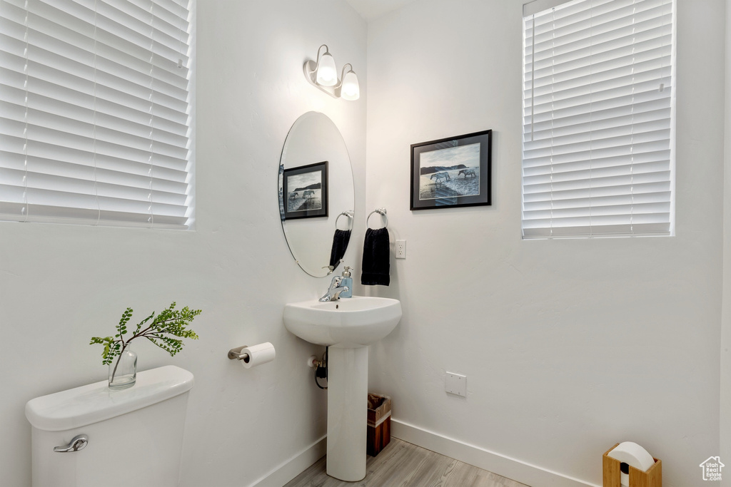 Bathroom featuring baseboards, toilet, and wood finished floors