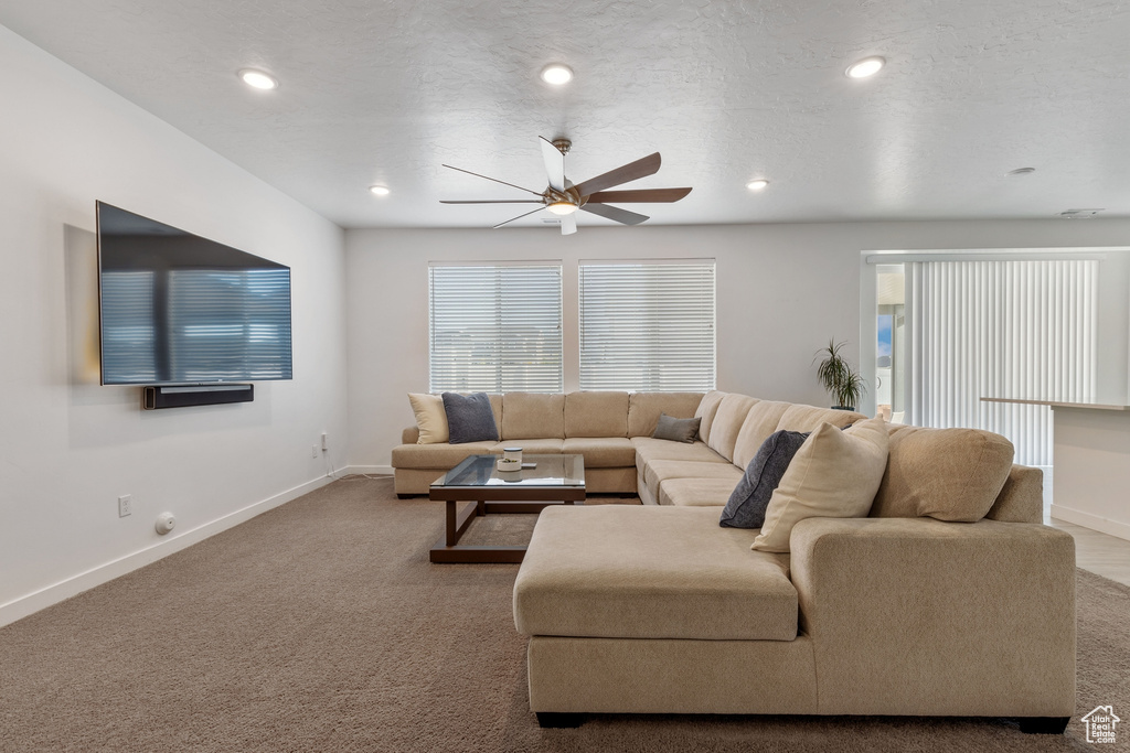 Carpeted living area featuring a ceiling fan, baseboards, and recessed lighting