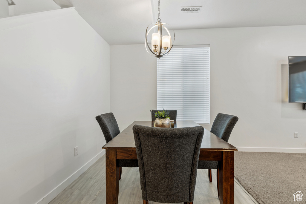 Dining area with baseboards, a chandelier, and light wood-type flooring