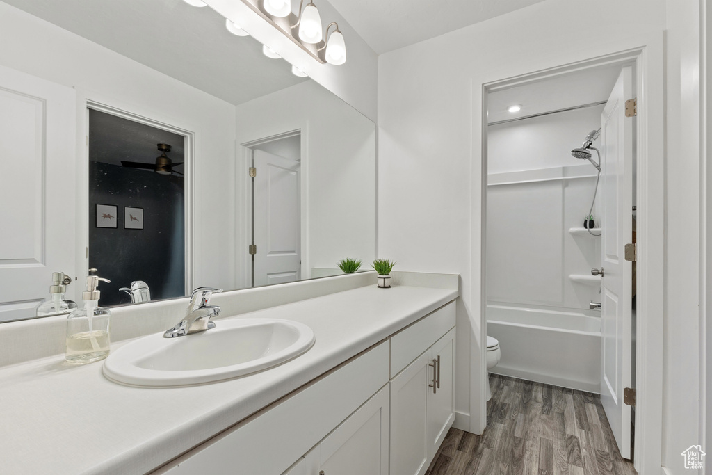 Full bathroom with vanity, toilet, wood finished floors, and washtub / shower combination