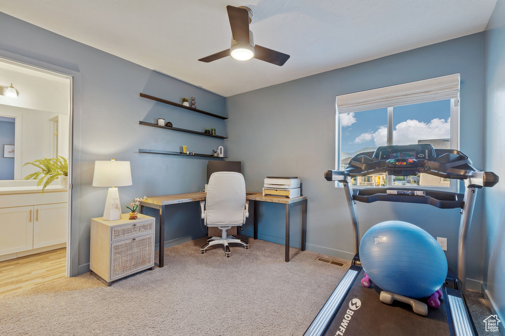 Carpeted office space with ceiling fan and baseboards