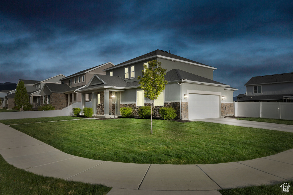View of front facade featuring stone siding, concrete driveway, and stucco siding
