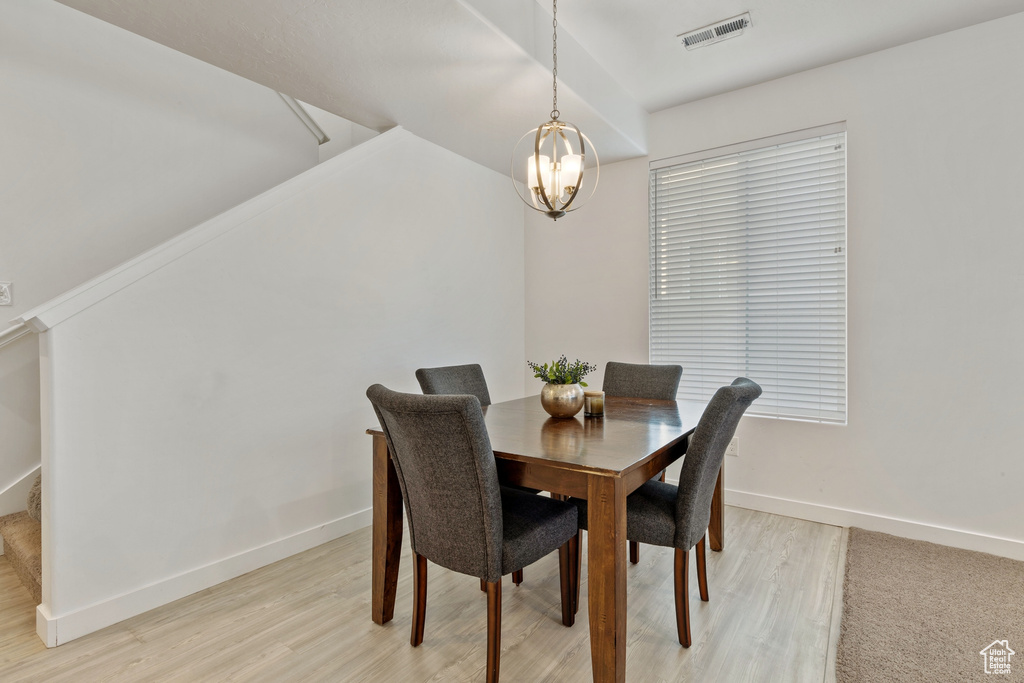 Dining area featuring light wood-type flooring, a chandelier, baseboards, and stairs