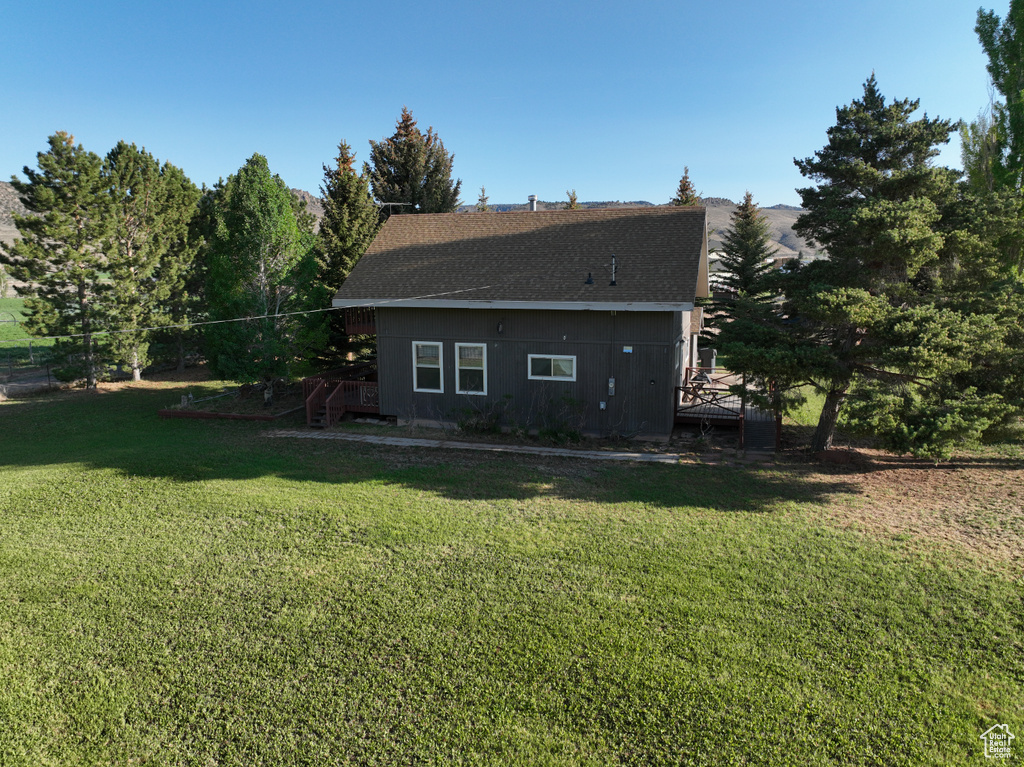 Back of house with a yard and roof with shingles