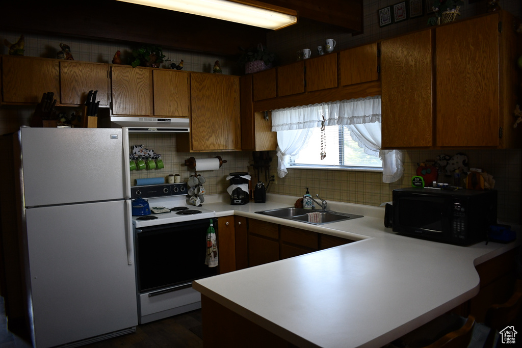 Kitchen with freestanding refrigerator, range with electric cooktop, a sink, black microwave, and backsplash