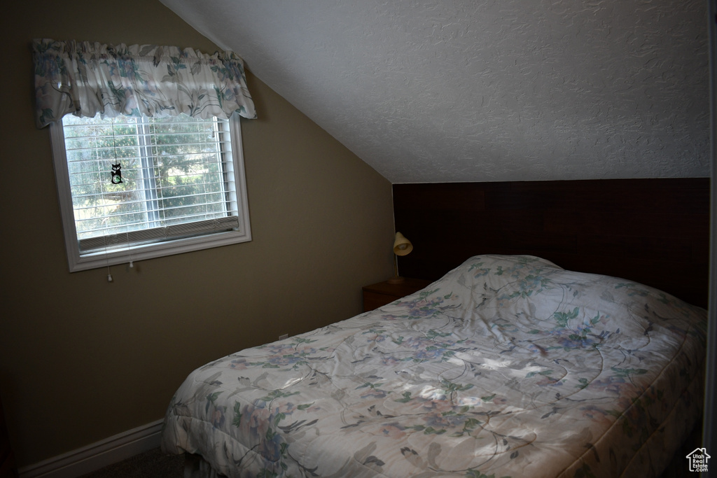 Bedroom with vaulted ceiling and a textured ceiling