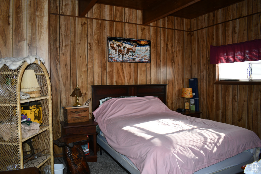 Bedroom featuring wooden walls, carpet flooring, and beamed ceiling