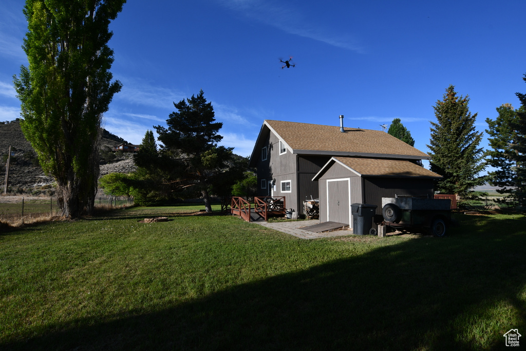 Back of property featuring a shingled roof and a wooden deck