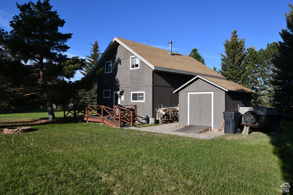 Back of house featuring a yard and a shingled roof