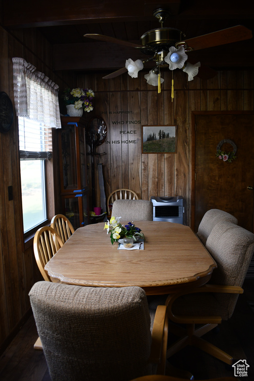 Dining area featuring wooden walls, ceiling fan, beam ceiling, and dark wood-style floors