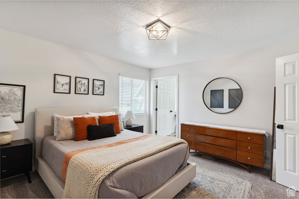 Bedroom with light colored carpet and a textured ceiling