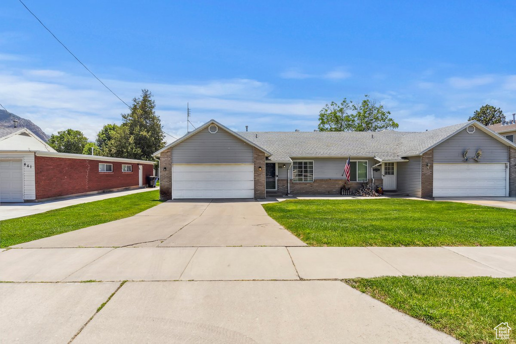 Single story home featuring brick siding, a front lawn, an attached garage, and concrete driveway