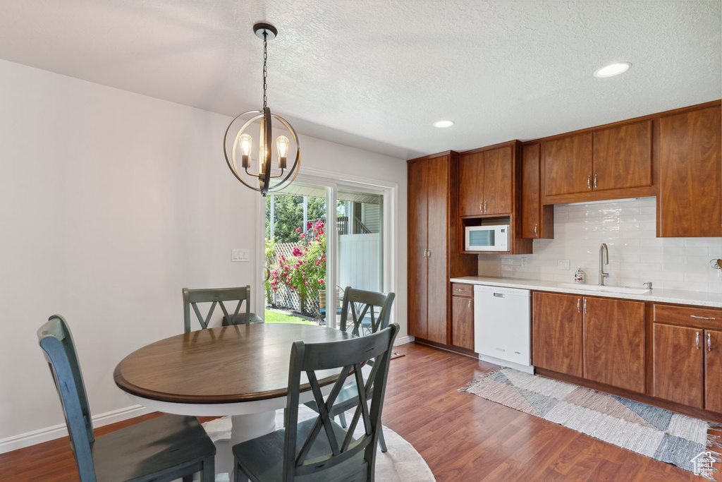 Kitchen with white appliances, light countertops, dark wood-style floors, a chandelier, and brown cabinets