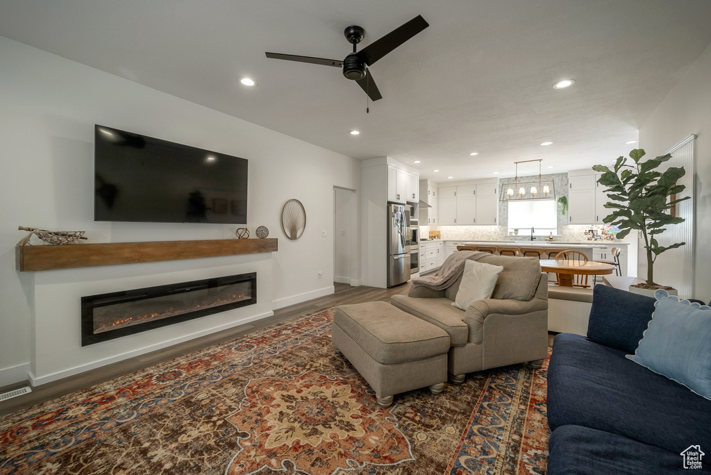 Living room featuring a ceiling fan, a glass covered fireplace, recessed lighting, and dark wood finished floors