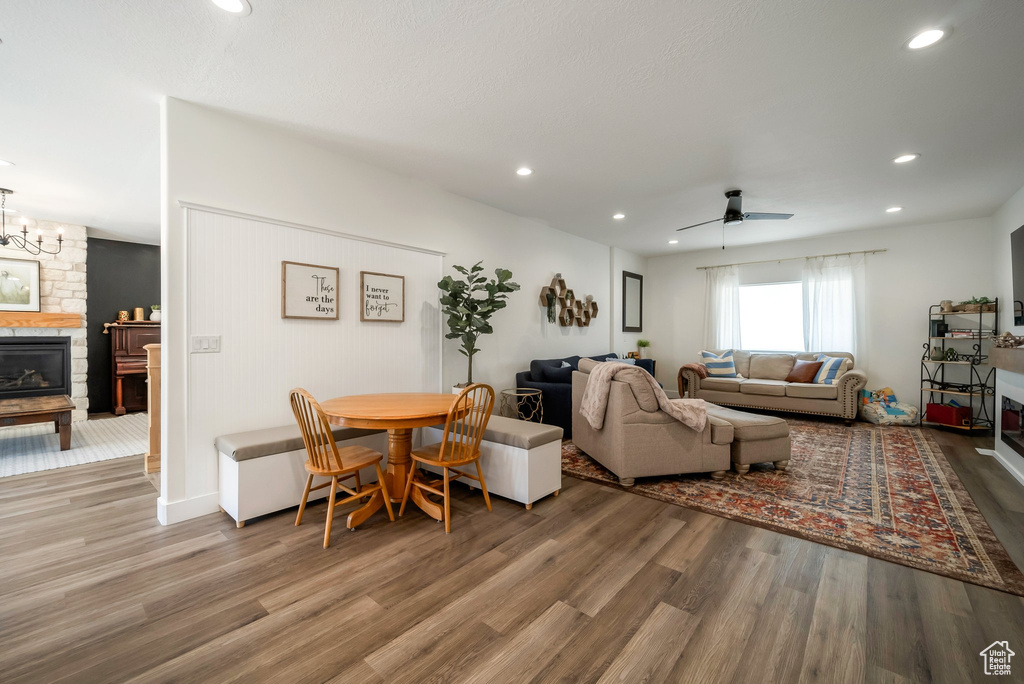 Living area with wood finished floors, a ceiling fan, recessed lighting, and a stone fireplace
