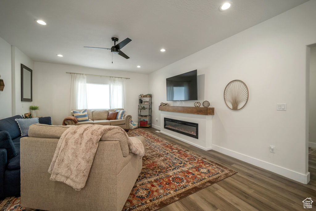 Living area with a ceiling fan, dark wood-style flooring, a glass covered fireplace, and recessed lighting