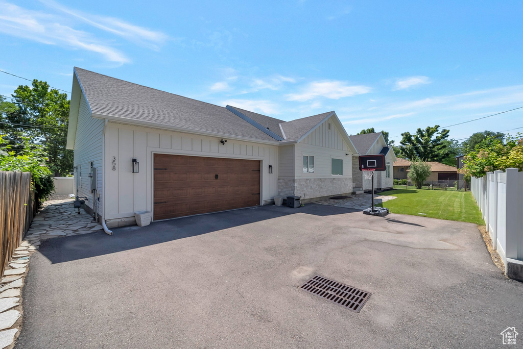 View of home\\\\\\\\\\\\\\\'s exterior with board and batten siding, an attached garage, roof with shingles, and asphalt driveway