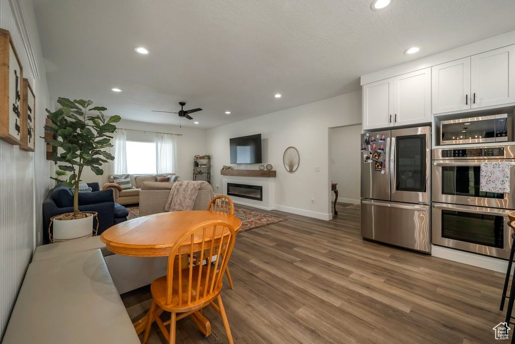 Dining area featuring a ceiling fan, recessed lighting, a glass covered fireplace, and wood finished floors