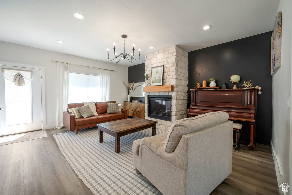 Living room with a chandelier, wood finished floors, recessed lighting, and a stone fireplace