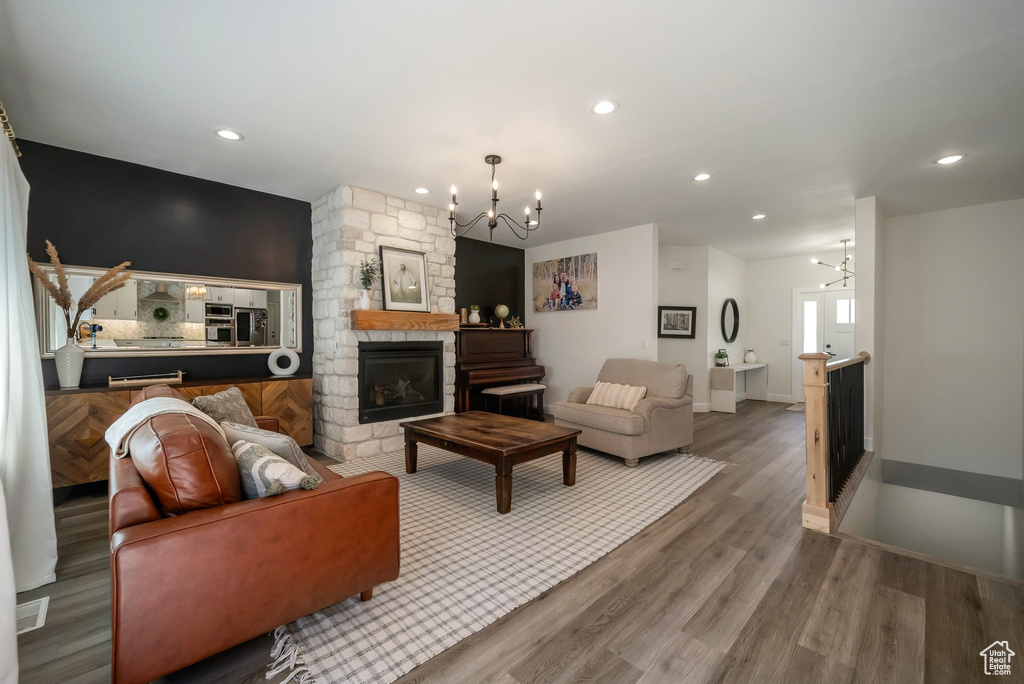 Living area with a chandelier, wood finished floors, recessed lighting, and a stone fireplace