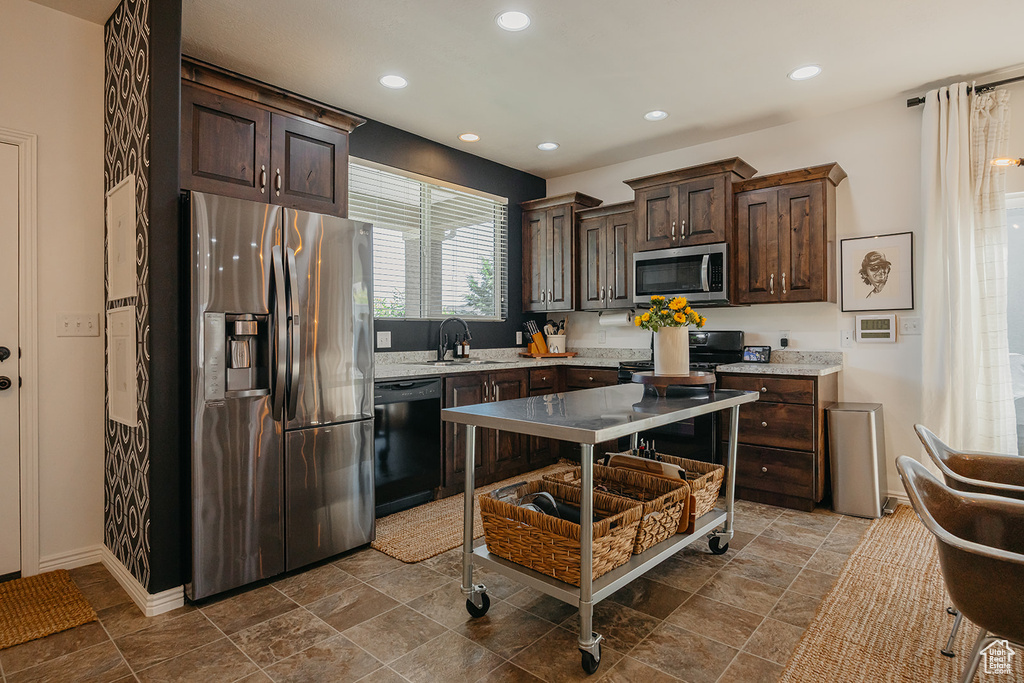 Kitchen with black appliances, dark brown cabinetry, recessed lighting, dark stone finish floors, and light stone countertops