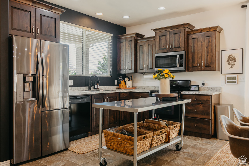 Kitchen featuring stainless steel appliances, dark brown cabinetry, light stone finish flooring, recessed lighting, and light stone counters