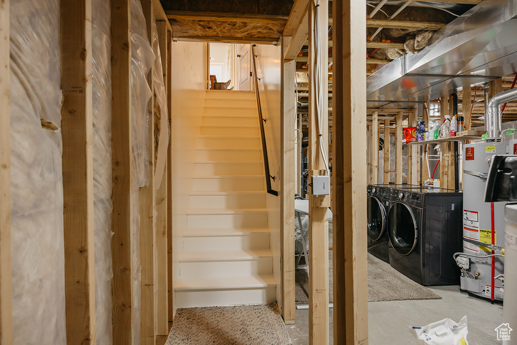 Unfinished below grade area with washer and clothes dryer, water heater, and stairway