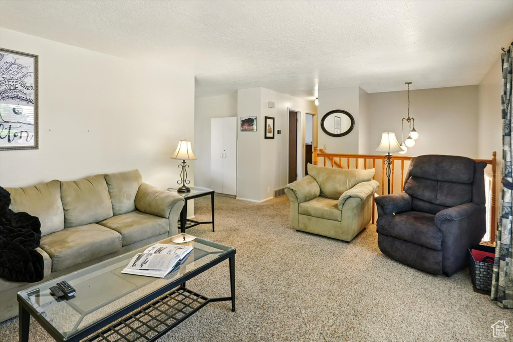 Carpeted living area featuring a textured ceiling and a chandelier