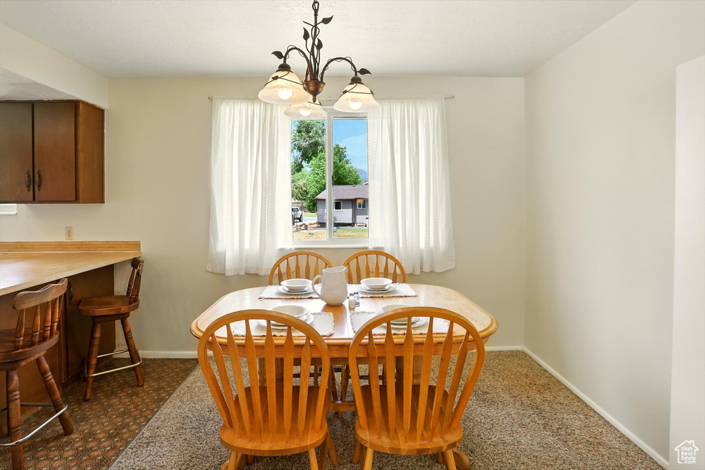 Dining space with a chandelier and dark colored carpet