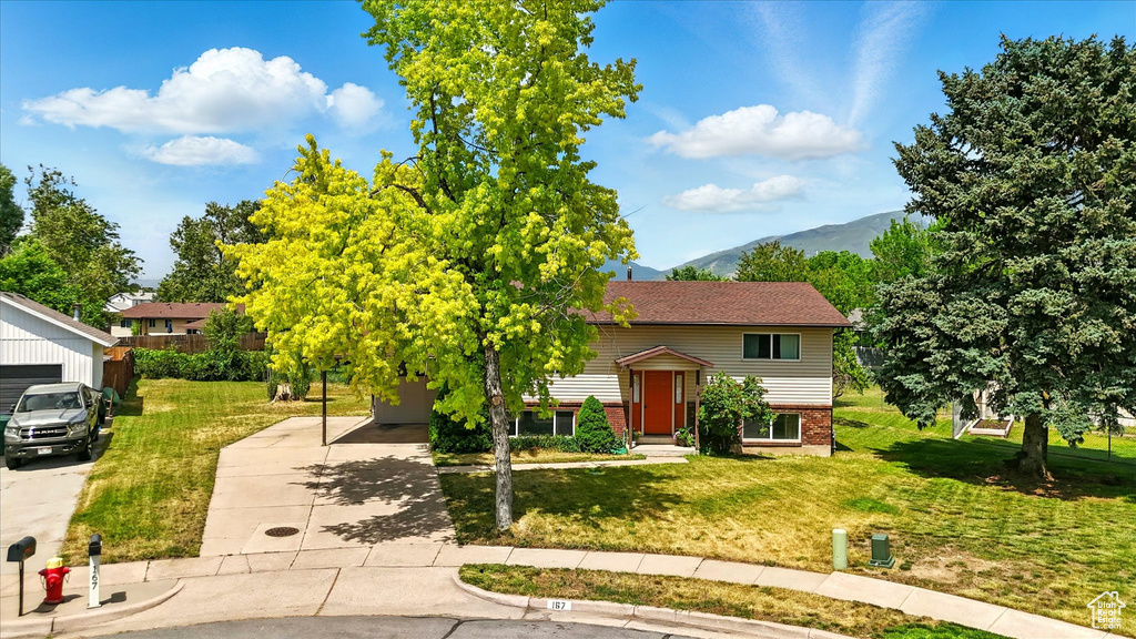Bi-level home featuring a mountain view, brick siding, a front yard, and driveway