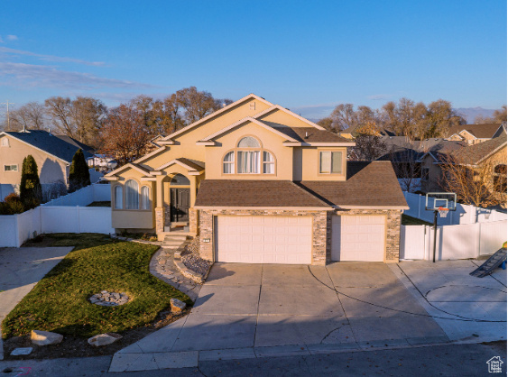 View of front of home with concrete driveway, a garage, stucco siding, roof with shingles, and brick siding