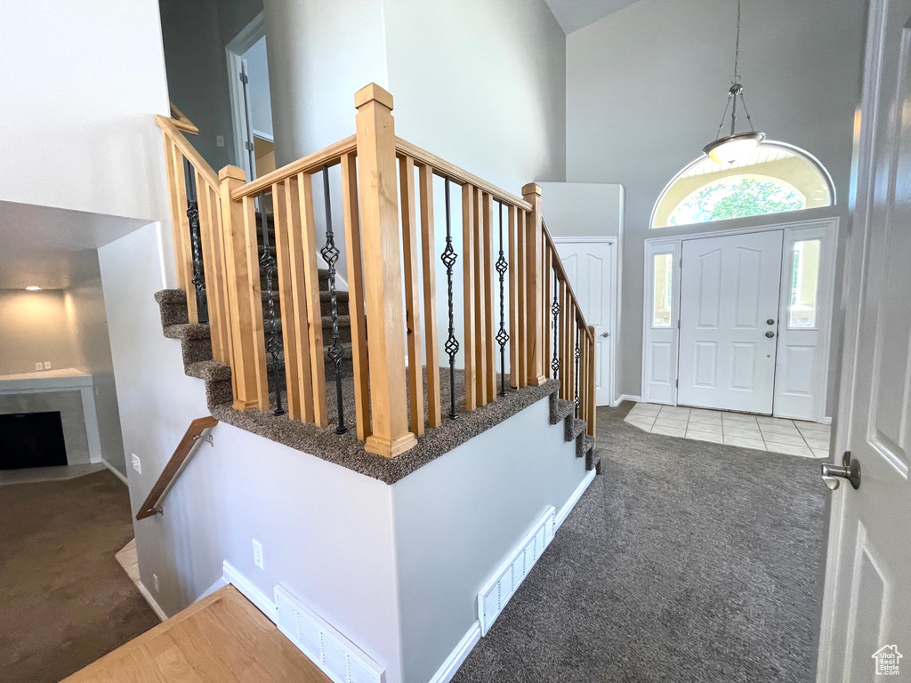Carpeted foyer entrance with a high ceiling, stairway, a fireplace, and tile patterned flooring