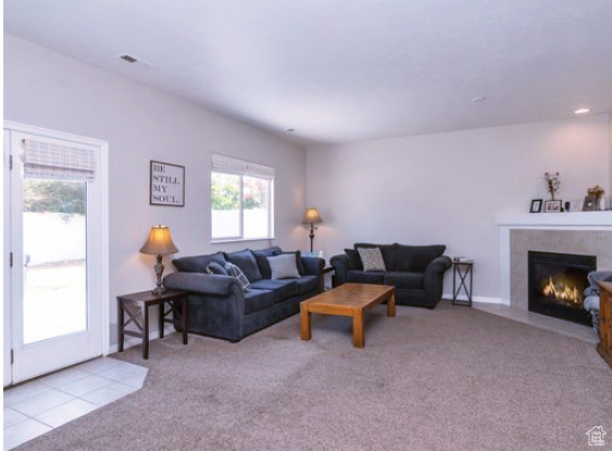 Living room featuring a glass covered fireplace and carpet flooring