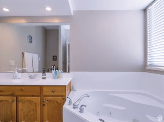 Full bath featuring a tub with jets, vanity, and recessed lighting